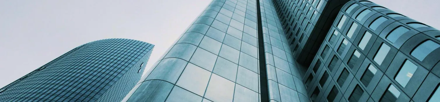 Blick nach oben auf moderne Glas-Hochhäuser in einer Stadt.