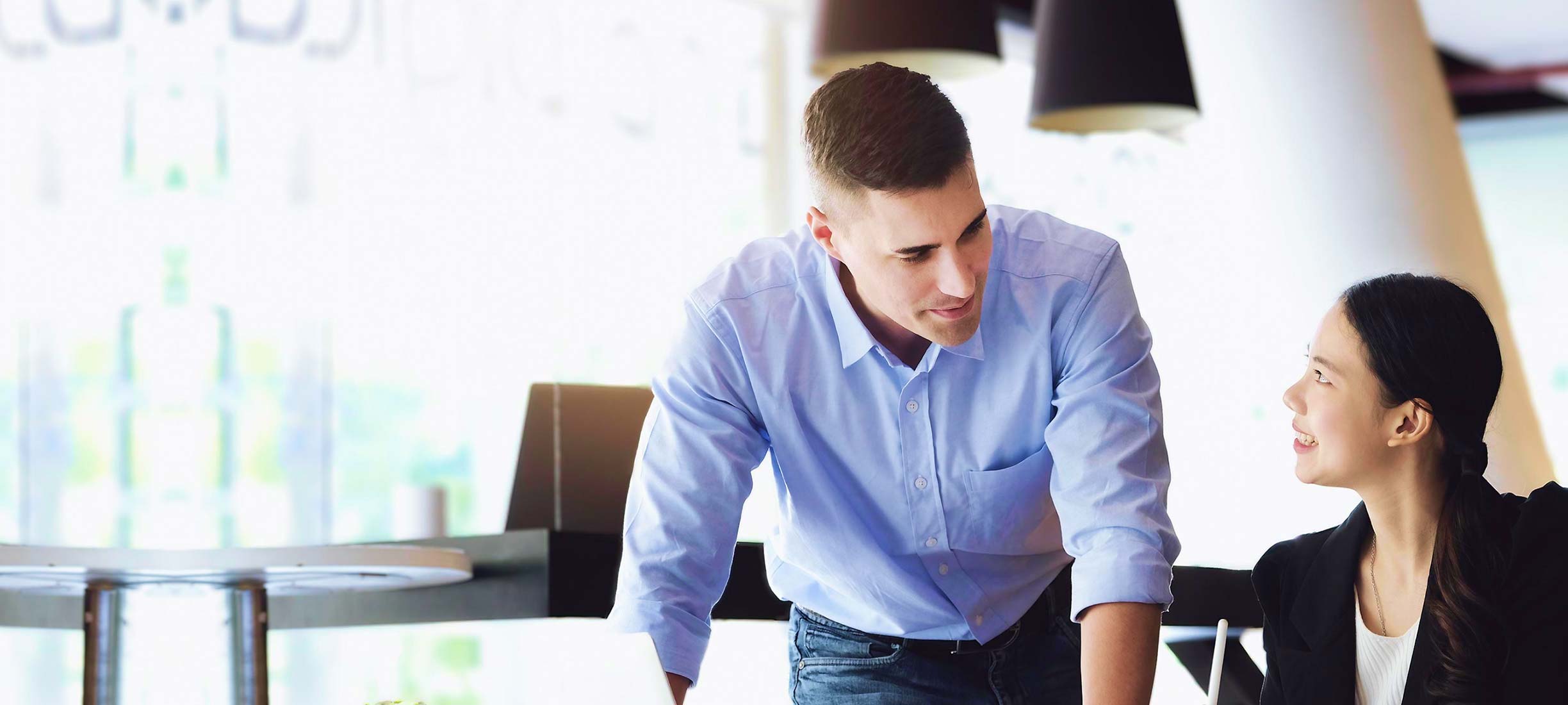 Mann und Frau besprechen etwas gemeinsam an einem Tisch im Büro.