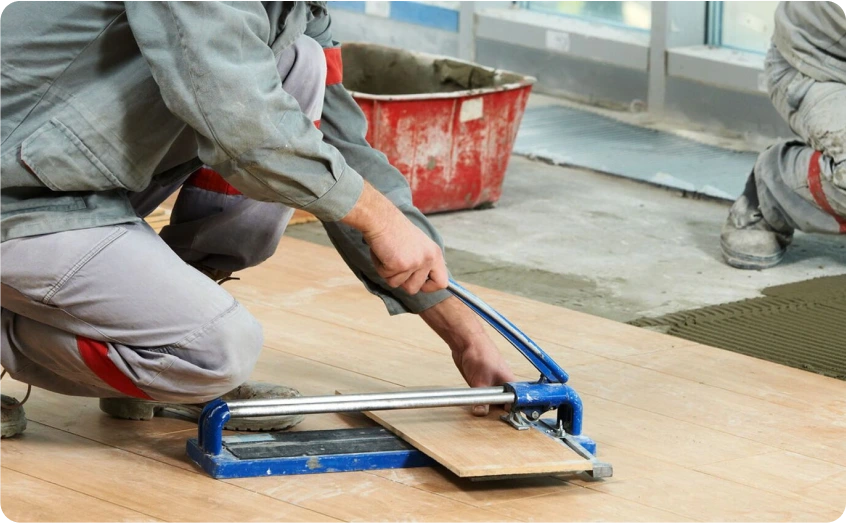 Handwerker schneidet Bodenfliesen mit einem Fliesenschneider.