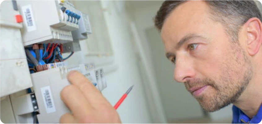 Elektriker prüft eine Sicherung im Sicherungskasten mit einem Schraubendreher.