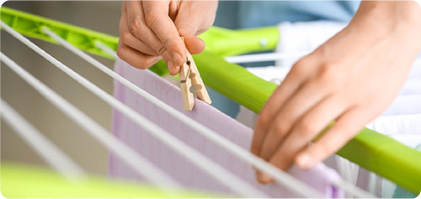 Hand hängt Wäsche mit einer Klammer an einen Wäscheständer.