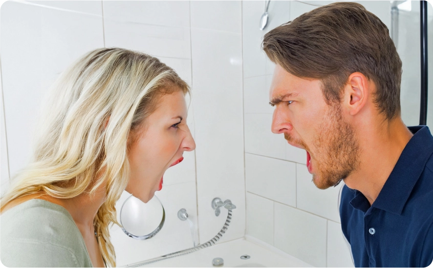 Mann und Frau streiten sich lautstark im Badezimmer.